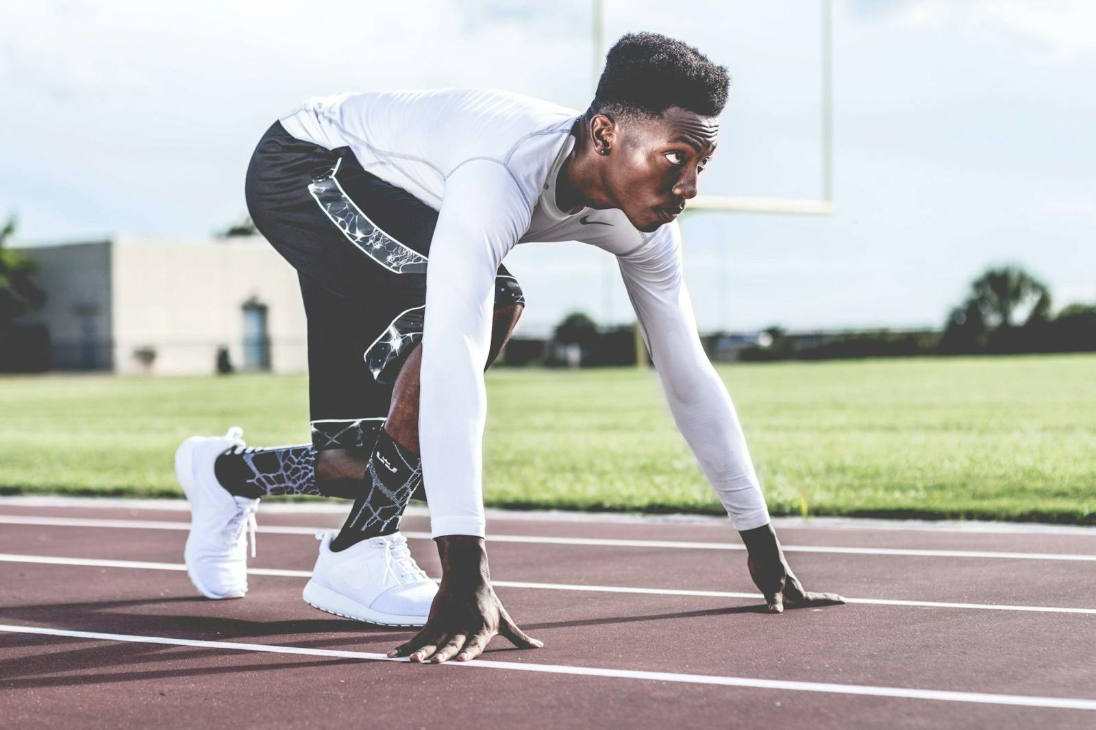 Becoming a Soldier - Focused athlete in starting position on a sunny track field, ready to sprint.